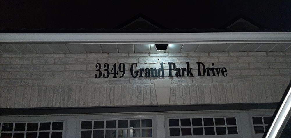 BigM  212 LED Solar Light is on in low light mode at the top of a house address signage