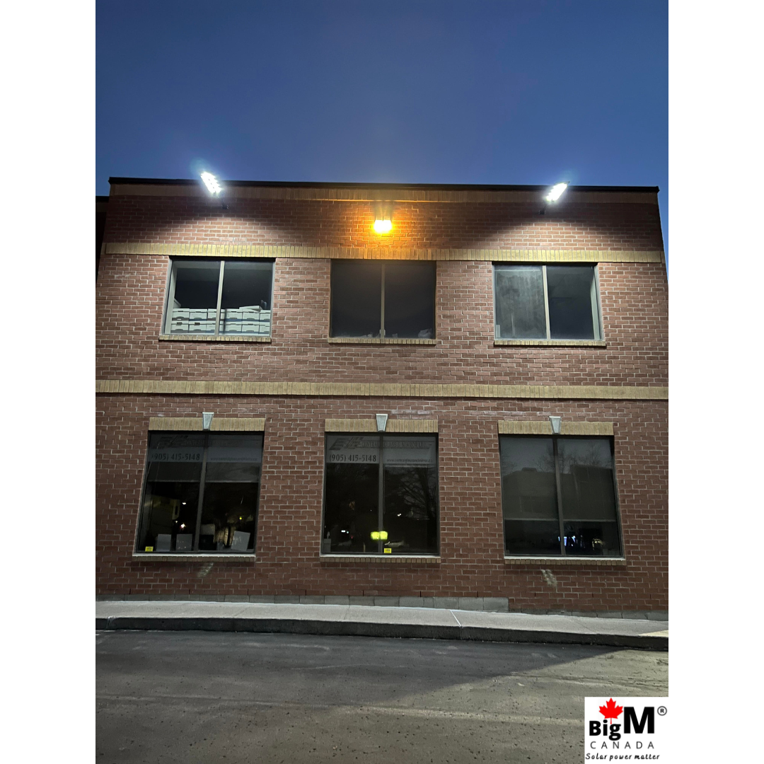 Image of BigM 900W Commercial Grade Solar Street Lights are lighting up a parking lot of a large commercial building