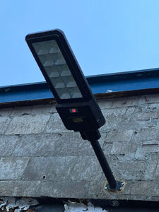 BigM  500W Solar Flood Lights with Motion Sensor for Outdoors is installed on the exterior wall of a commercial building