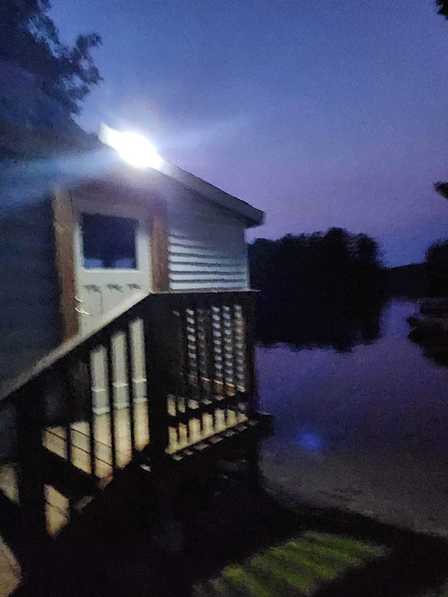 BigM 190 LED Bright Outdoor Solar Security Lights with Motion Sensor illuminates a lakeside cottage at night