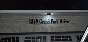 BigM  212 LED Best Solar Security Light is on in low light mode at the top of a house address signage