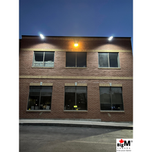 Load image into Gallery viewer, Image of BigM 900W Commercial Grade Solar Street Lights are lighting up a parking lot of a large commercial building
