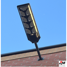 Load image into Gallery viewer, Image of BigM 900W Commercial Grade Solar Street Lights installed at the outside wall of a commercial building
