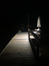 Load image into Gallery viewer, Night view of BigM 100 w street light that being installed by customer by the lake on a deck
