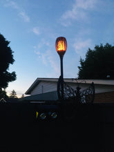 Cargar imagen en el visor de la galería, BigM 96 LED Solar Dancing Flame Lights mounted above a fence beside a walk way
