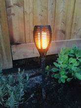 Load image into Gallery viewer, BigM LED Solar Powered Flickering Flame Lights is turn on at night in a garden
